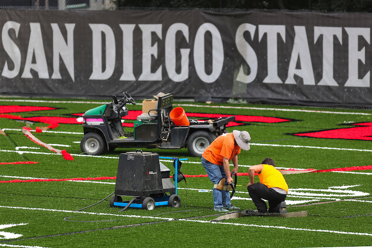 Workers install FieldTurf at an SDSU practice field