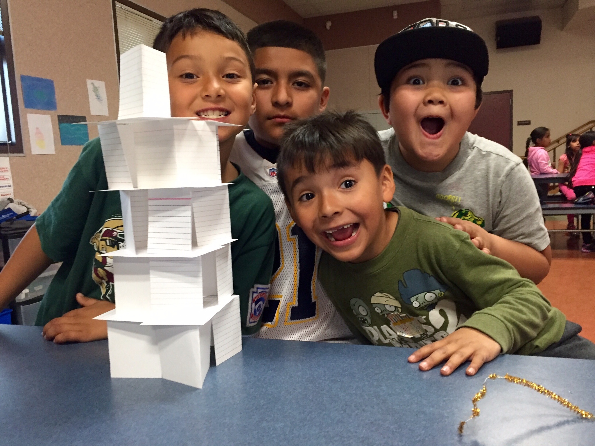Kids posing by a paper tower they built