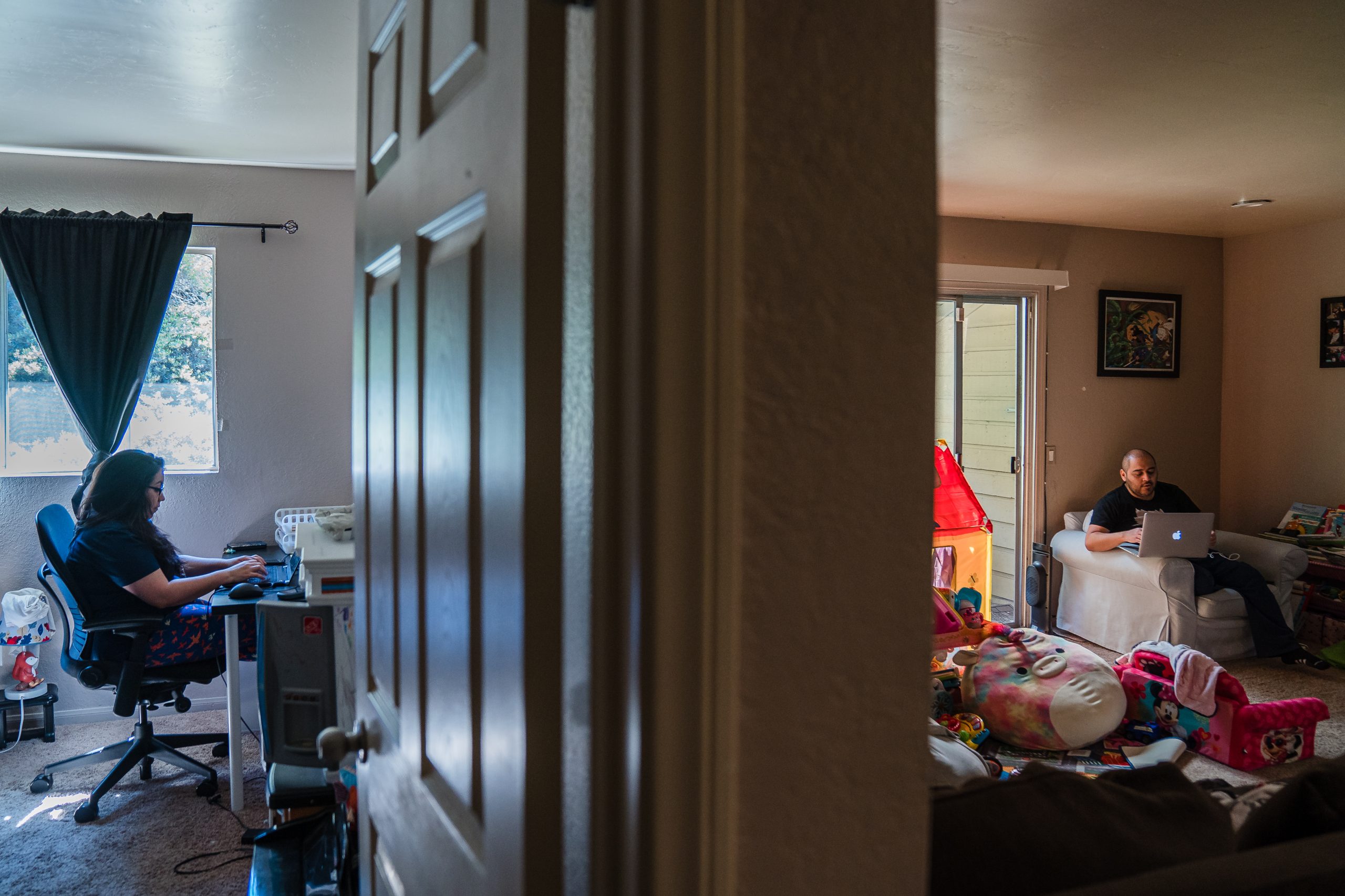 Sophia Rodriguez an employee with the County of San Diego works in a bedroom while her husband Dan, a software quality assurance engineer works in the living room while also watching the kids at home in Chula Vista on March 8, 2022.