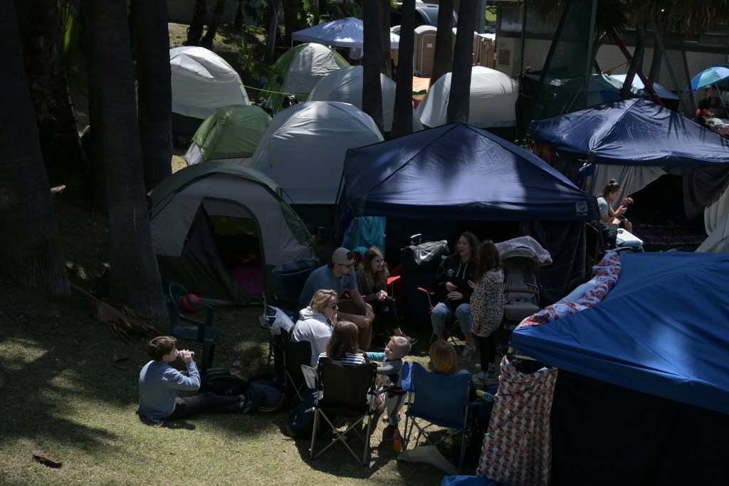 Ukrainian refugees turn a bus stop into a make-shift camp to wait their turn to claim asylum in the United States in Tijuana, Mexico on Monday, April 4, 2022. / Photo by Carlos A. Moreno for Voice of San Diego