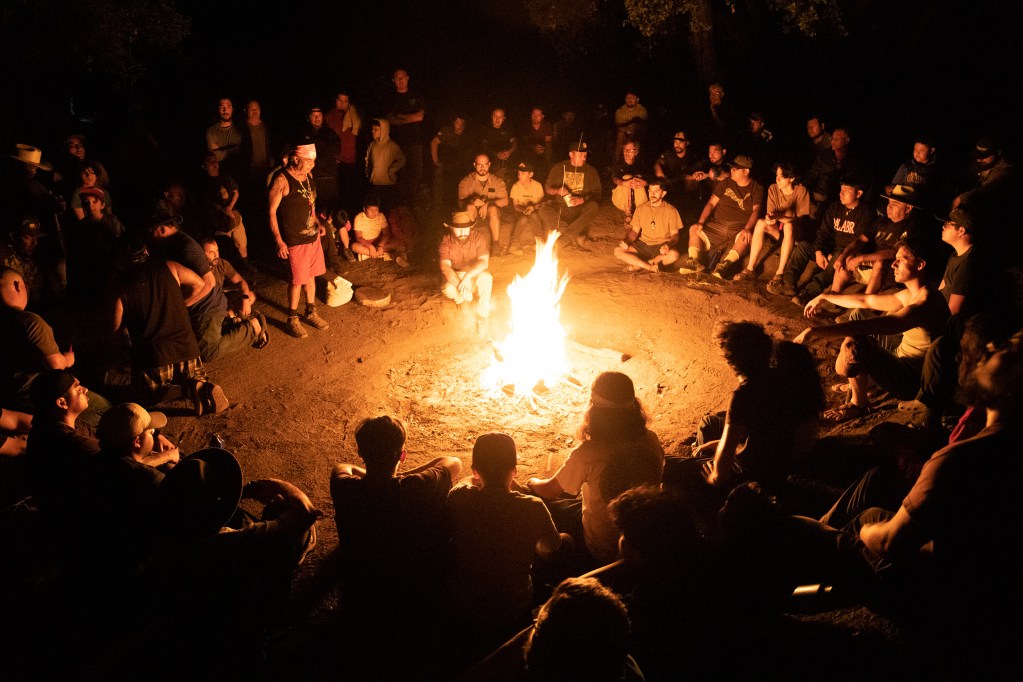 The men gather around the fire to sing and pray. / Photo by Jakob McWhinney
