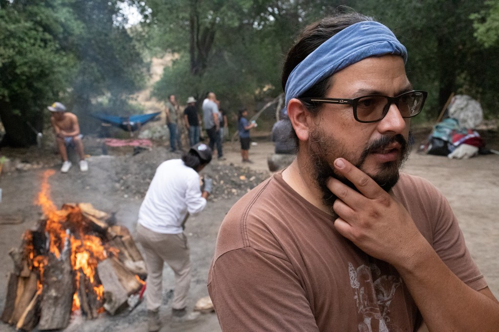 German Gurrola speaks as men warm stones for the sweat lodges. / Photo by Jakob McWhinney