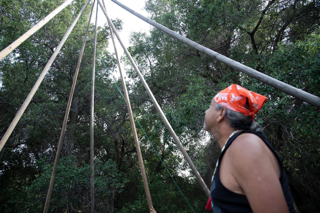 Macedonio Arteaga looks up at the teepee’s frame. / Photo by Jakob McWhinney