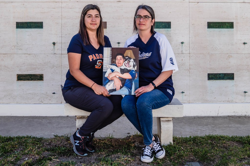 Ashely Jepsen (left) and Stephanie Campbell (right) hold a painting of their brother Dale Campbell II at Eternal Hills Mortuary and Crematory on Nov. 22, 2022, who passed away from complications from Covid-19.