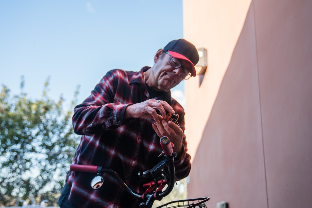 Micheal Weidekemper, 58 years old, works on his bike at La Posada de Guadalupe shelter in Carlsbad on Dec. 13, 2022.