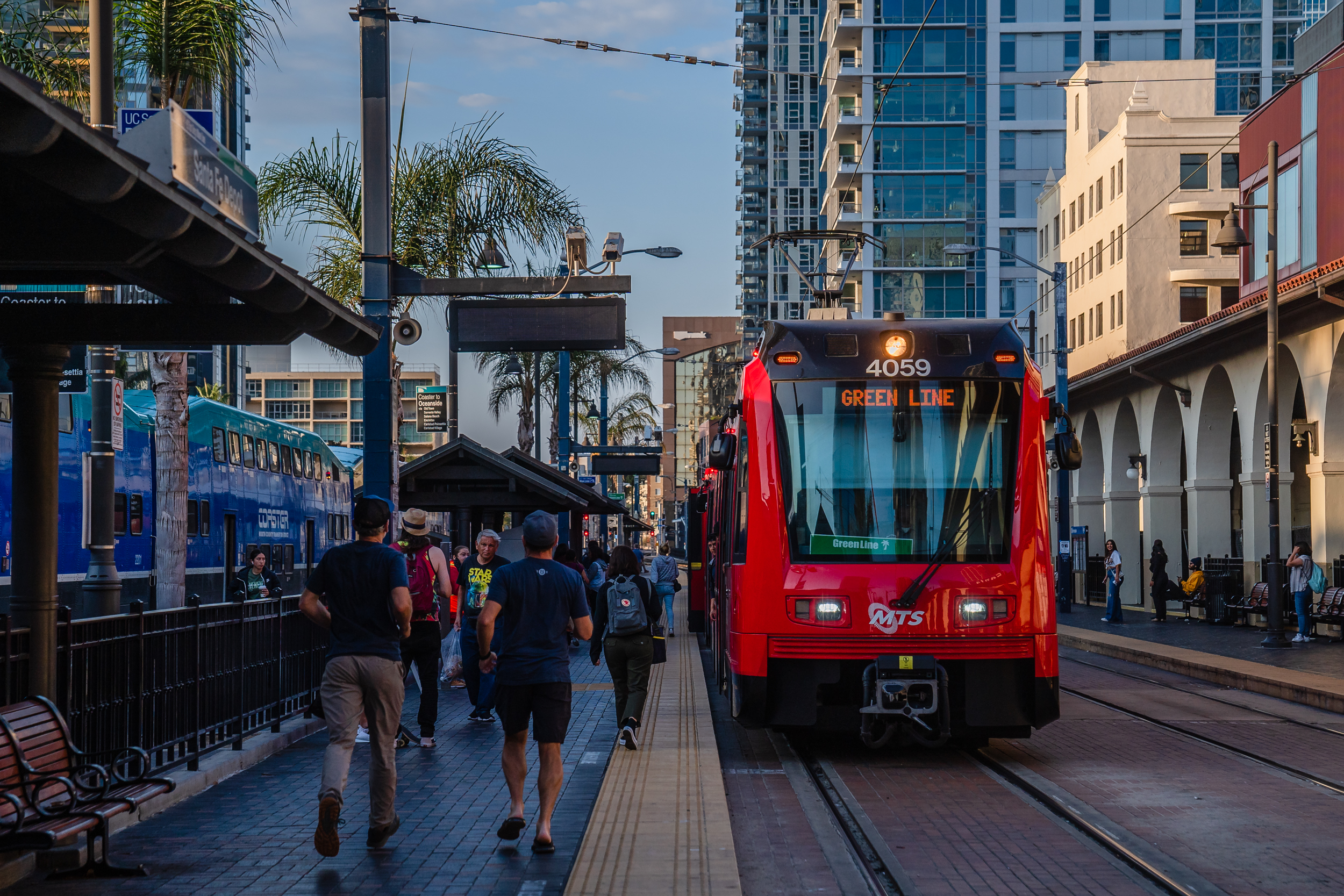 People walk near the Green Line trolley at the Santa Fe Depot in downtown on Oct. 4, 2022.