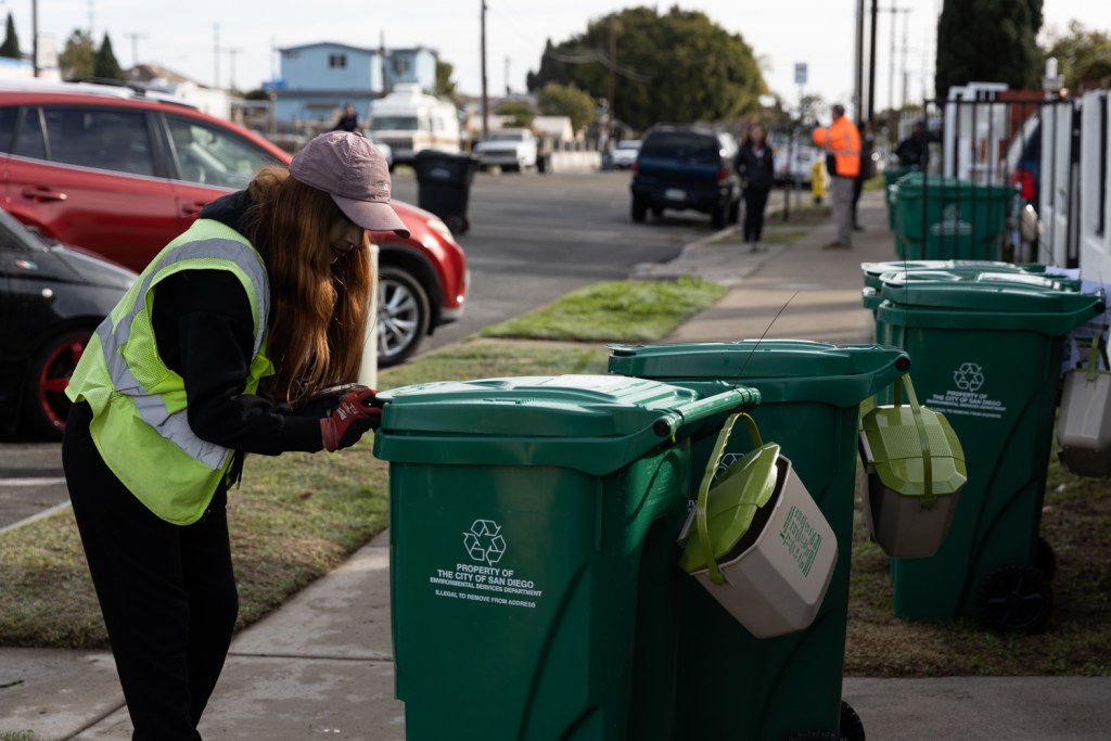 Gomez Garcia, a contractor, scans and registers new food waste bins in the Sherman Heights neighborhood on Jan. 11, 2023.