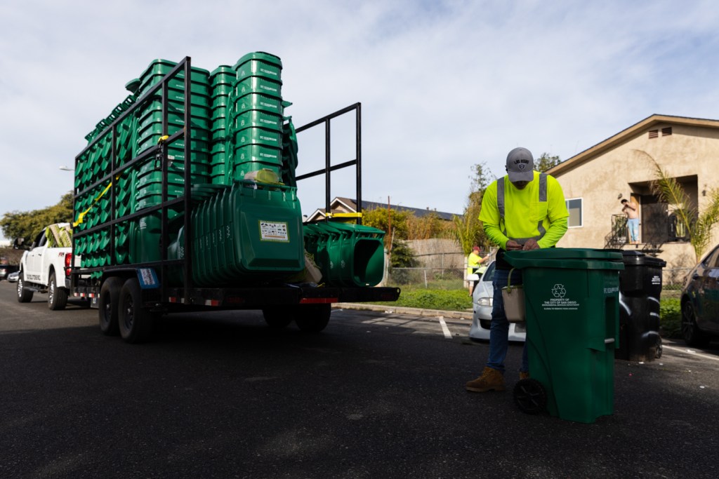 A contract worker attaches a kitchen pail to a new food waste bin in the Sherman Heights neighborhood on Jan. 11, 2023.