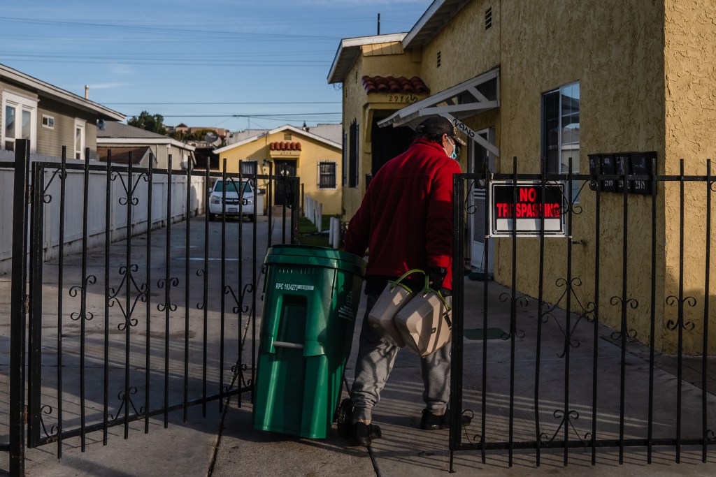 Julio Gomez walks towards his home with his kitchen pails and new waste bin after it was dispensed by the waste collector in Grant Hill on Jan. 18, 2023.