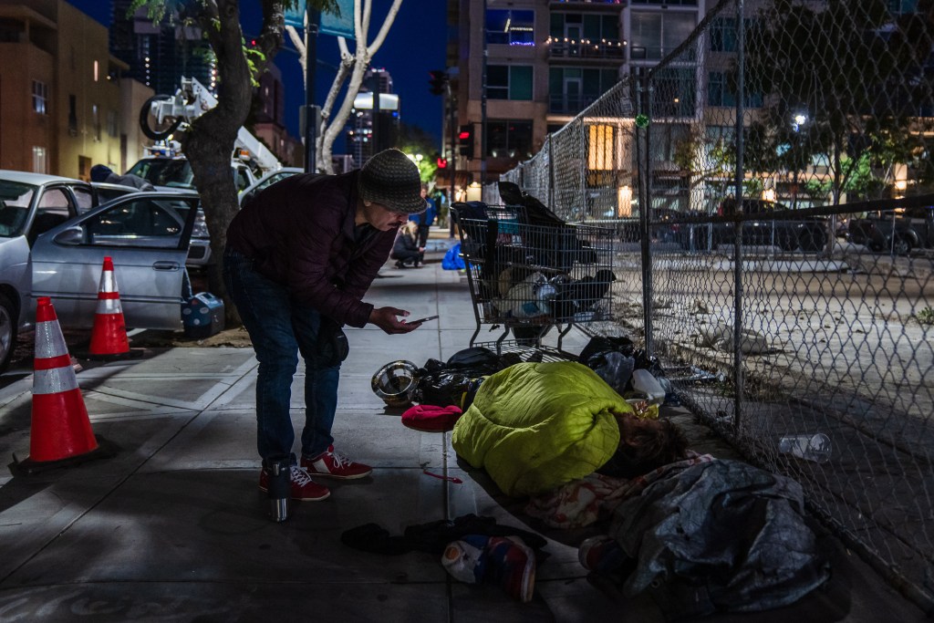A volunteer from state Sen. Toni Atkins' office talks to an unhoused person during the in downtown San Diego during the annual point in time count on Jan. 26, 2023. / Photo by Ariana Drehsler