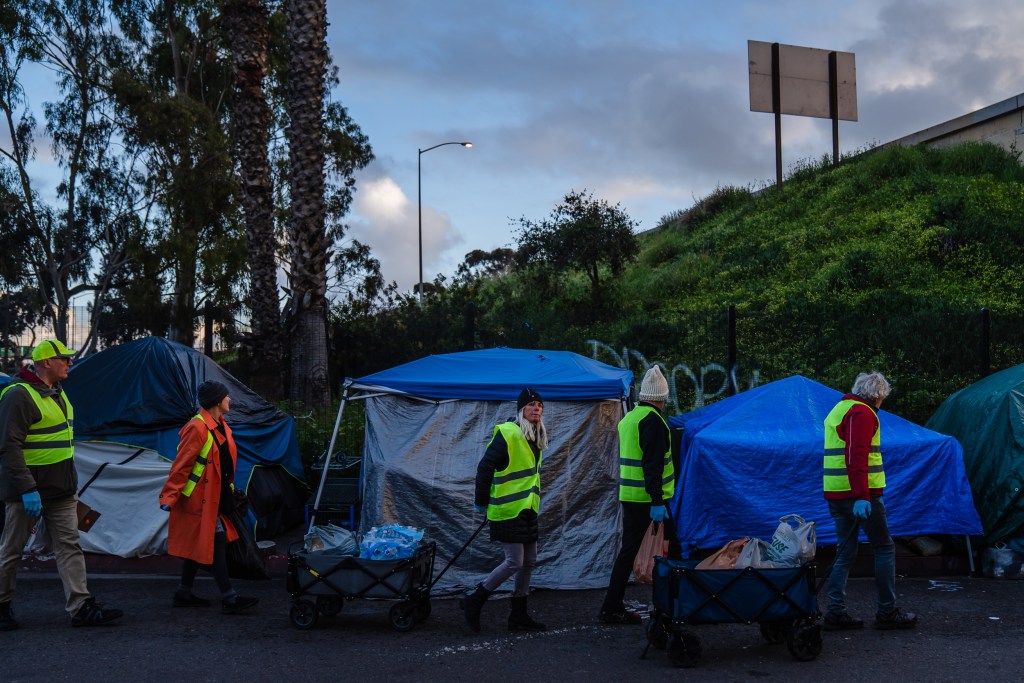 A group of friends that are volunteers bring food, water and blankets to people living in a homeless encampment on Commercial Street in downtown on March 30, 2023.