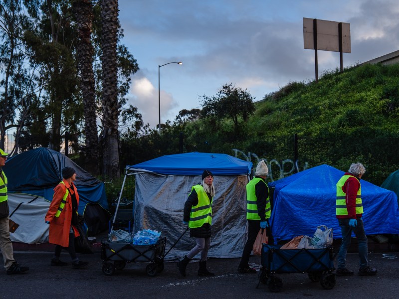 A group of friends that are volunteers bring food, water and blankets to people living in a homeless encampment on Commercial Street in downtown on March 30, 2023.