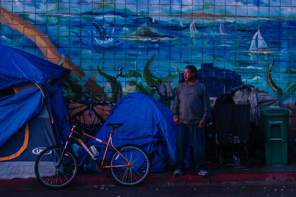 A man stands near his tent on Commercial Street Street in downtown on March 30, 2023.