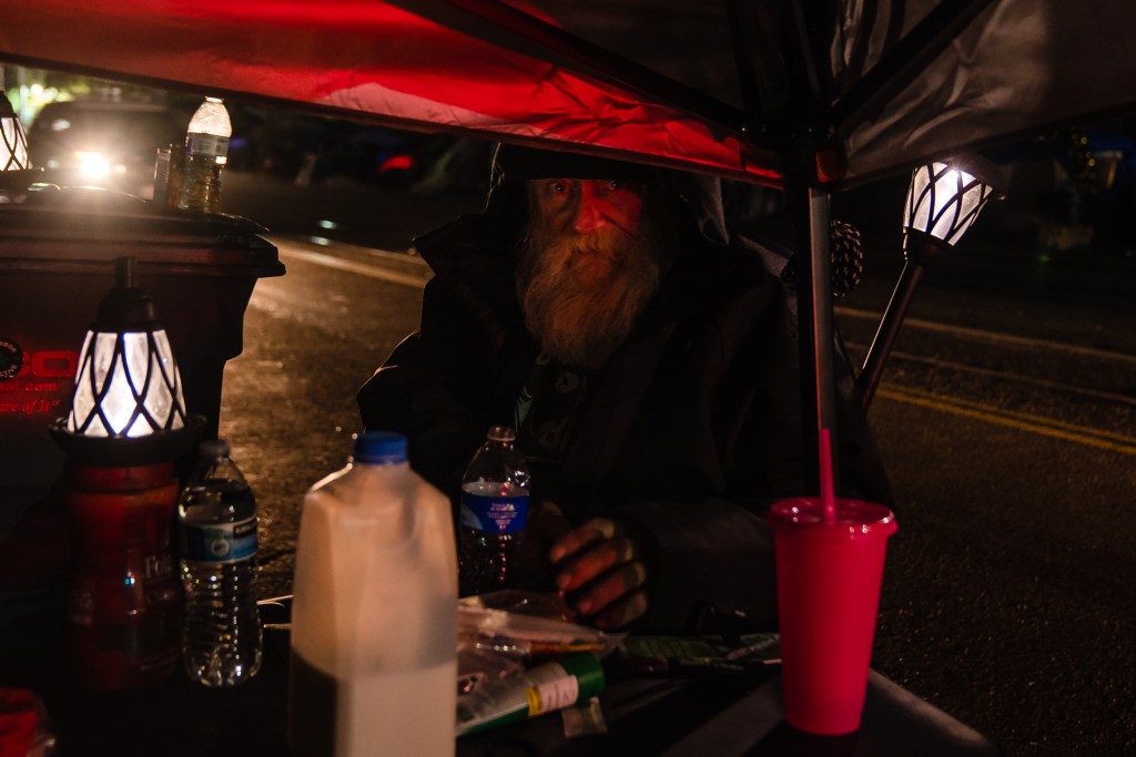 A unhoused man sits outside underneath a freeway underpass on Commercial Street in downtown on March 30, 2023.