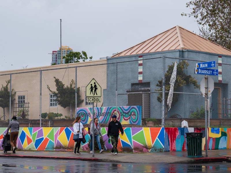 People walk next to Perkins Elementary School in Logan Heights on March 14, 2023.
