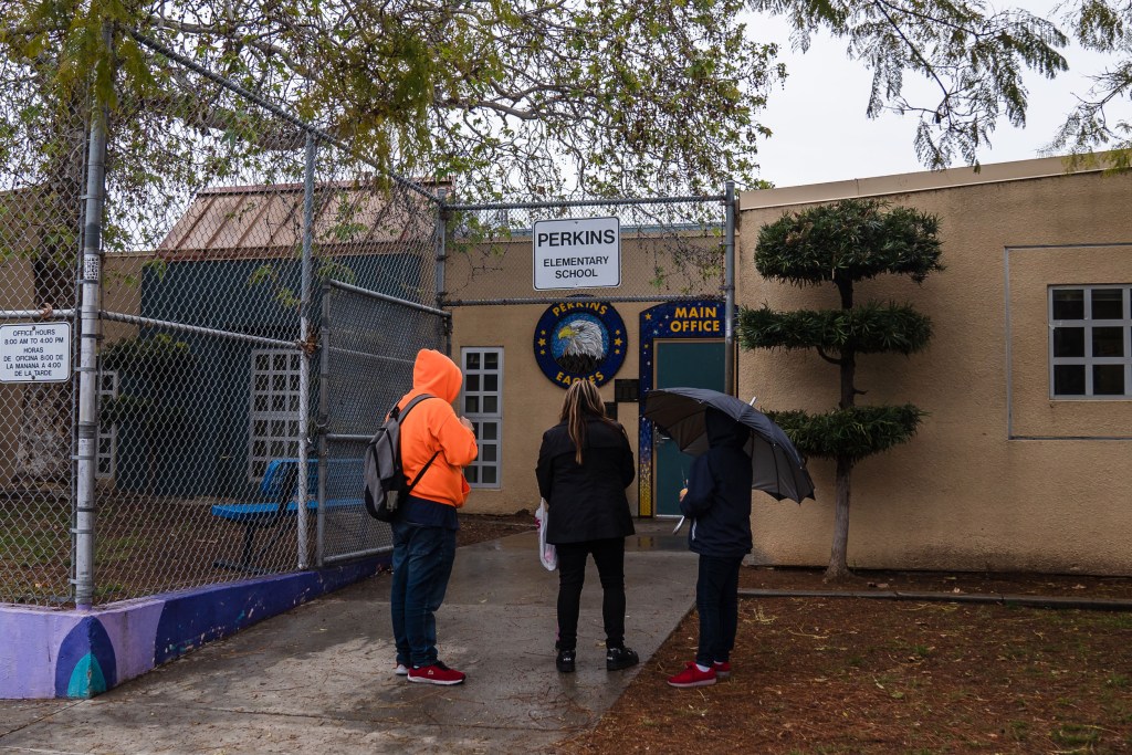 People stand in front of Perkins Elementary School in Logan Heights on March 14, 2023.