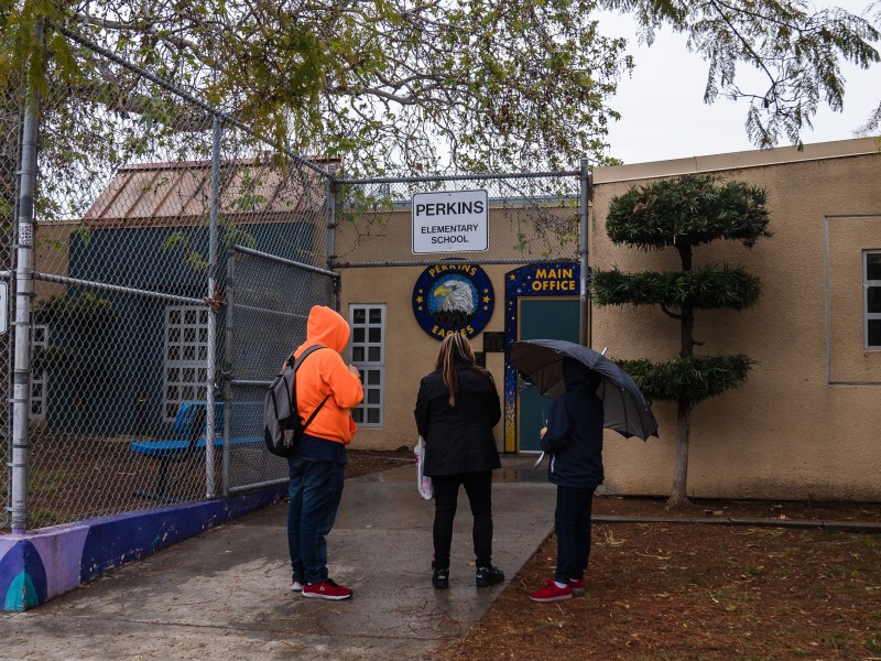 People stand in front of Perkins Elementary School in Logan Heights on March 14, 2023.