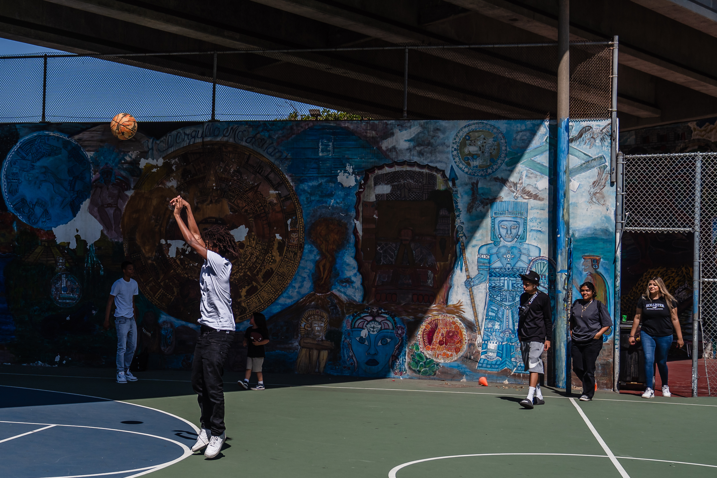 Young men play basketball in Barrio Logan on Chicano Park Day on April 22, 2023.