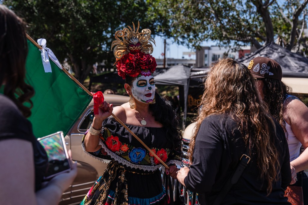 A woman wearing Día De Los Muertos makeup poses for a photo in Barrio Logan to celebrate Chicano Park Day on April 22, 2023.