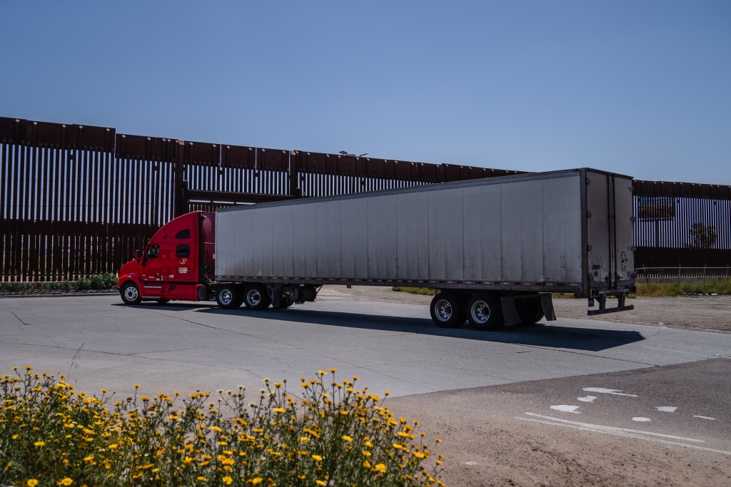 A cargo truck passes the border wall that divides the United States and Mexico in Otay Mesa on April 26, 2023.