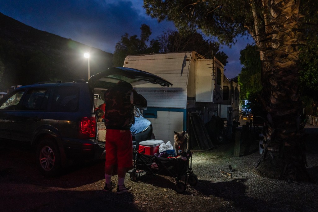 Tami Grobarek and William Pendarvis get some of their belongings out of the car to put in their wagon before making their way to a nearby hillside to set up their tent for the night in El Cajon on May 9, 2023.