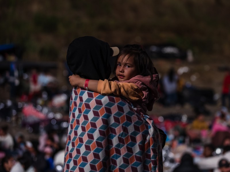 Asylum seekers can be seen through the border wall in San Ysidro on May 11, 2023.