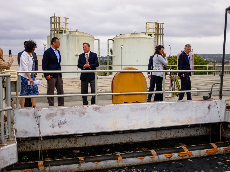 California Sen. Alex Padilla talks with South Bay International Wastewater Treatment Plant Area Operations Manager Morgan Rogers on June 5, 2023. The two overlook the overloaded primary treatment system.