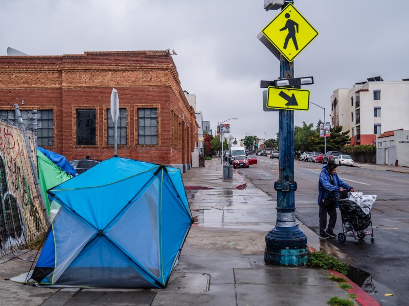 A woman walks passed a tent on National Avenue in the East Village on June 14, 2023.