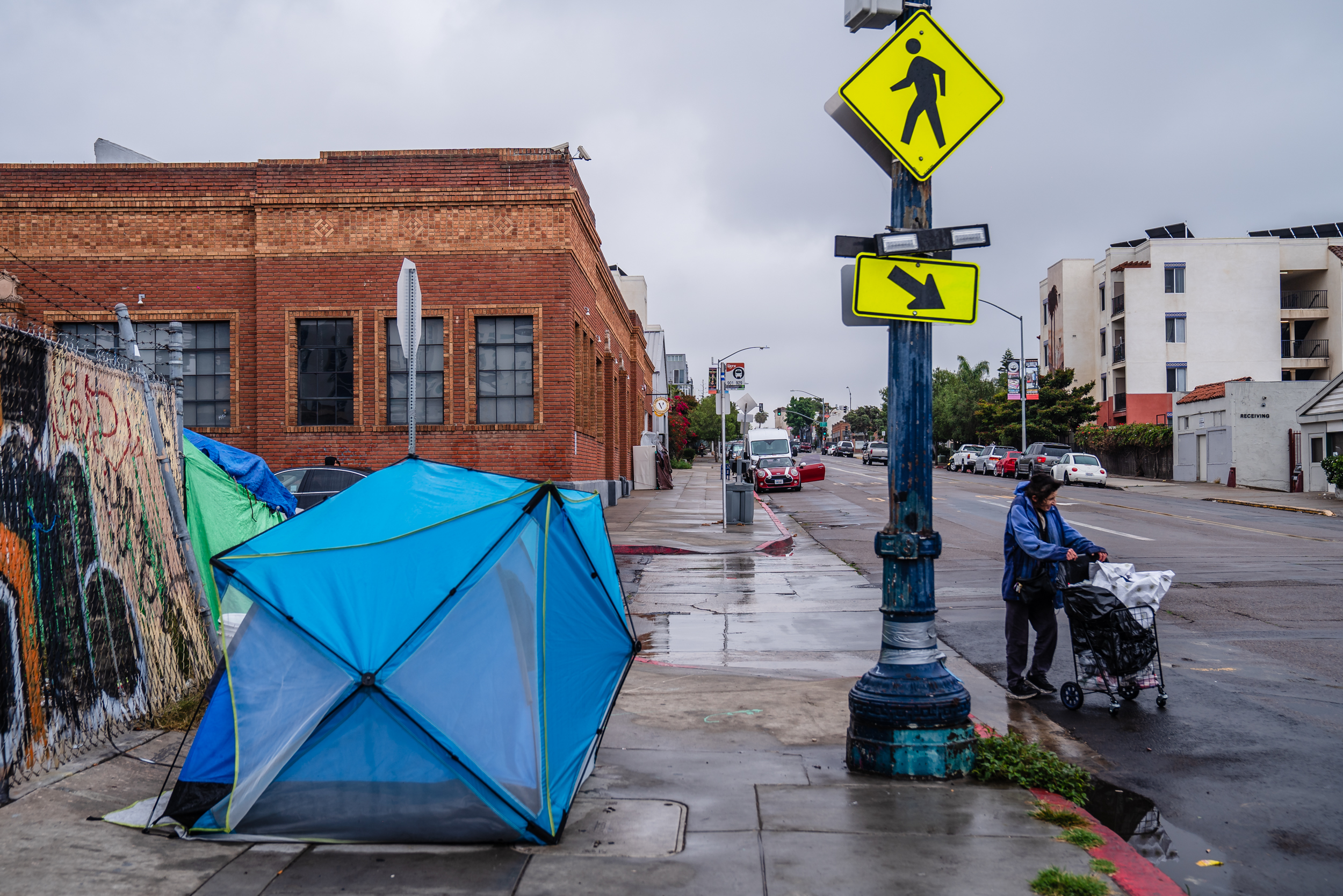 A woman walks passed a tent on National Avenue in the East Village on June 14, 2023.