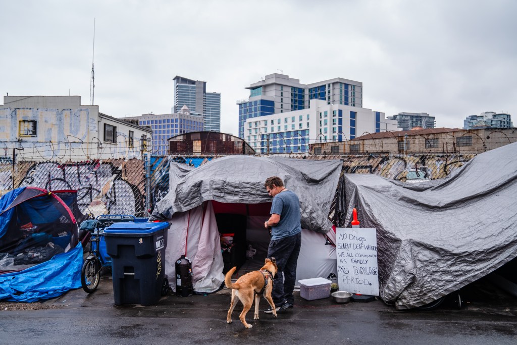 Brian Byrd stands in front of his tent with his dog on 16th Street in the East Village on June 14, 2023.