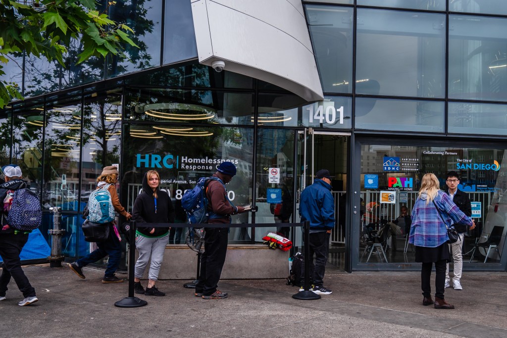 People that are unhoused stand in line early morning outside of the Homelessness Response Center in the East Village waiting to see if they will be able to stay in shelter on June 5, 2023.