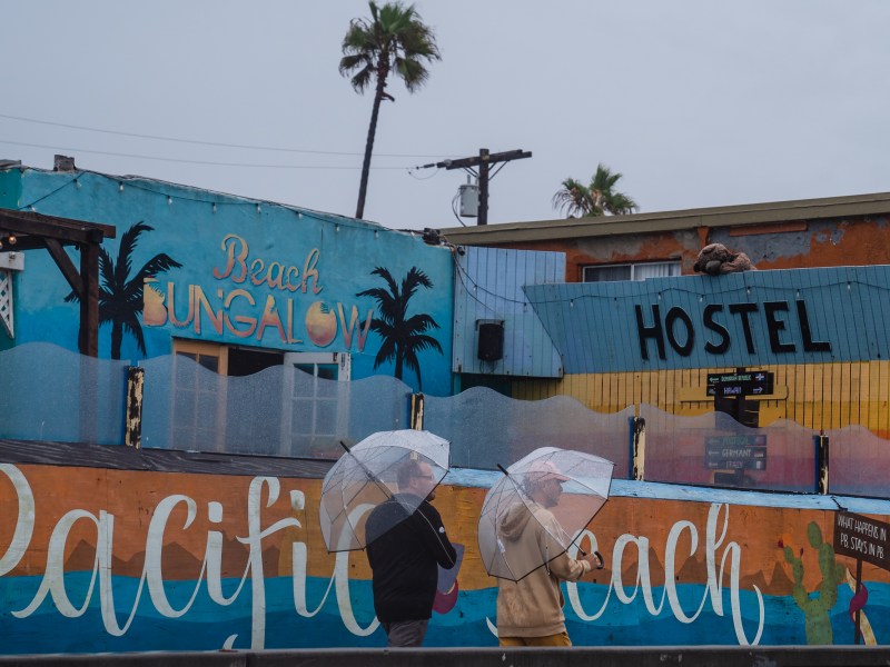 Men walk on the boardwalk in Pacific Beach before tropical storm Hilary makes landfall on Aug. 20, 2023.
