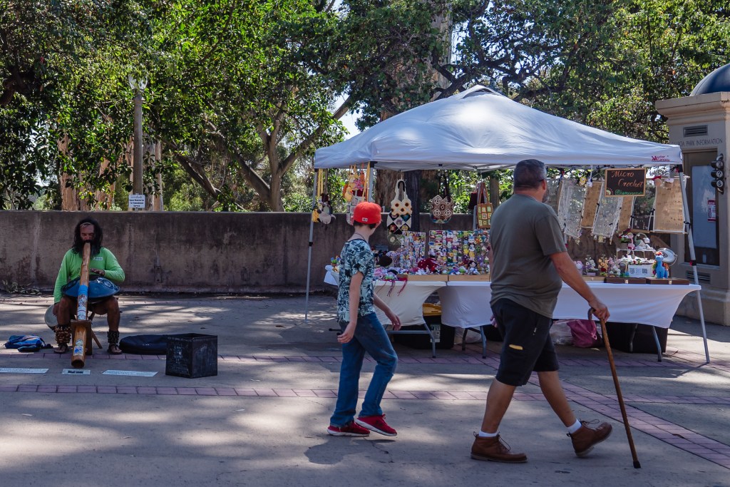 People walk passed a vendor at Balboa Park on Sept. 14, 2023.