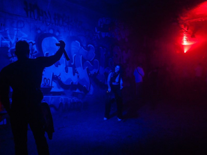 A man lights a woman so a friend can take a photo in an underground tunnel.