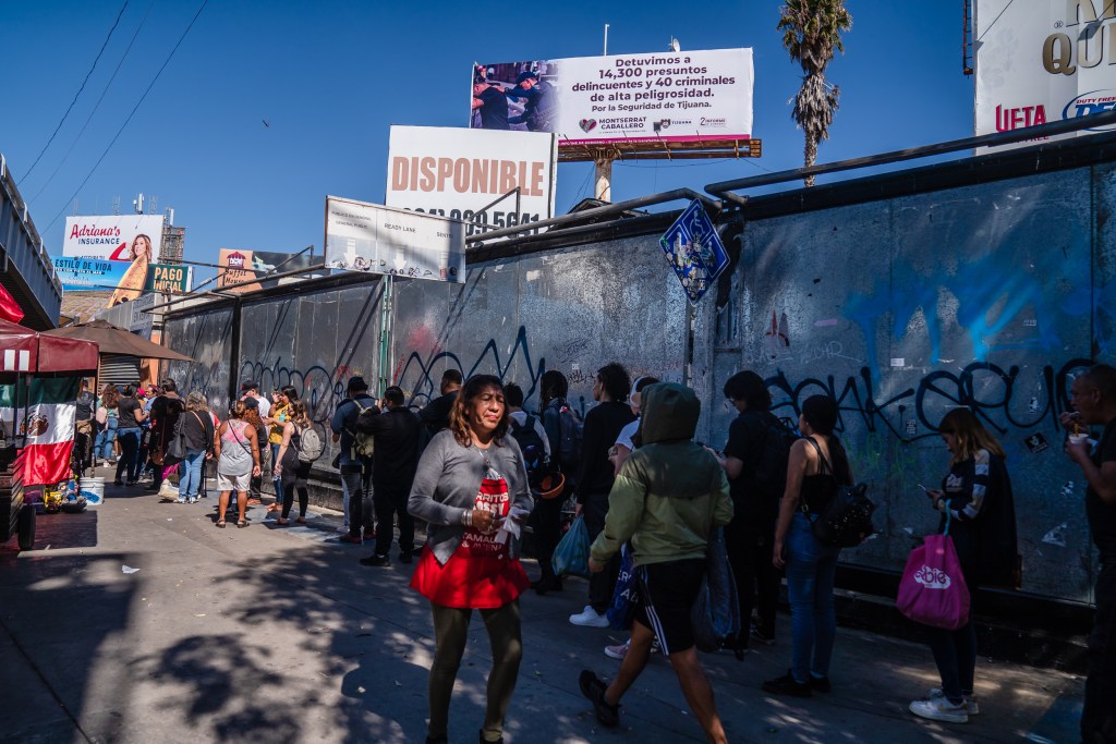 People wait in a long line border crossing to enter the United States from Tijuana on Oct. 6, 2023.