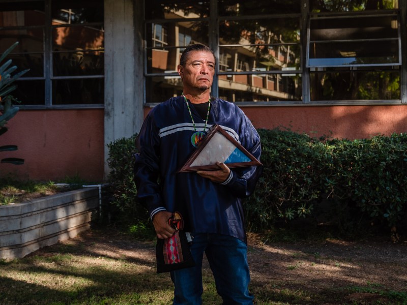 Bobby Wallace of the Barona Band of Mission Indians poses for a photo while holding the Kumeyaay flag at San Diego Unified in University Heights on Nov. 3, 2023.