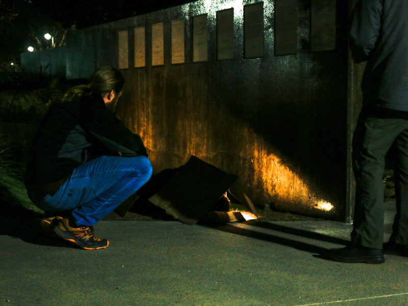 A volunteer with the Regional Taskforce on Homelessness conducting the annual point-in-time count speaks to a man sleeping on a sidewalk in downtown Vista on Thursday, Jan. 25, 2024. / Photo by Tigist Layne