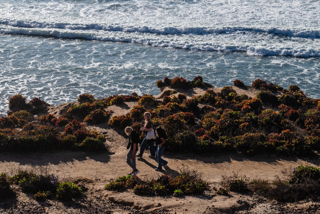People walk near the ocean in Del Mar on Jan. 2, 2024.