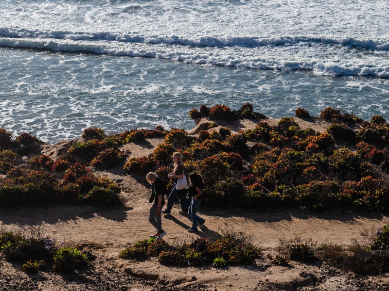 People walk near the ocean in Del Mar on Jan. 2, 2024.