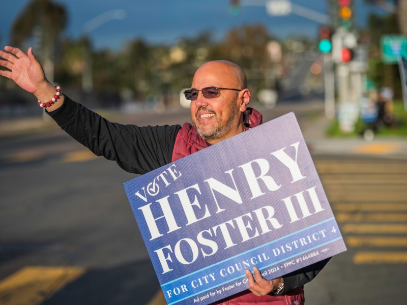Henry Foster III waves to early morning commuters on Imperial Ave in San Diego, CA, in an effort to elect him to City Council District 4 on Presidential Primary Election Day, March 5, 2024. / Photo by Vito di Stefano for Voice of San Diego