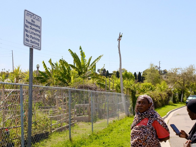 Fatima Abdelrahman, a Sudanese refugee, and Sahar Abdalla, outside the New Roots Community Farm. A sign next to the garden fence says, "property of the city of San Diego," but the ownership of the land is being disputed. / Photo by MacKenzie Elmer
