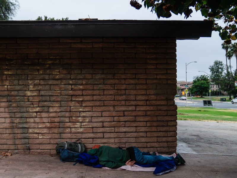 A homeless person sleeps on the ground at a park near Old Town on July 17, 2024. / Ariana Drehsler for Voice of San Diego