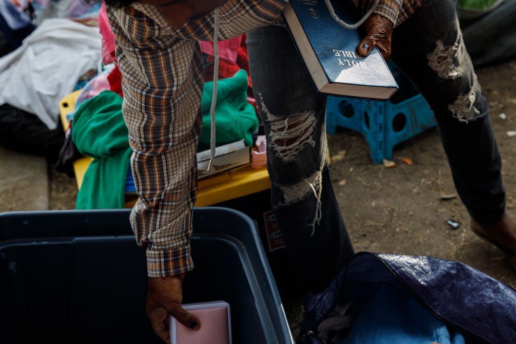 A man from Nicaragua organizes his family’s belongings at an encampment in San Diego on Aug. 7, 2024. / Photo by Kristian Carreon for Voice of San Diego