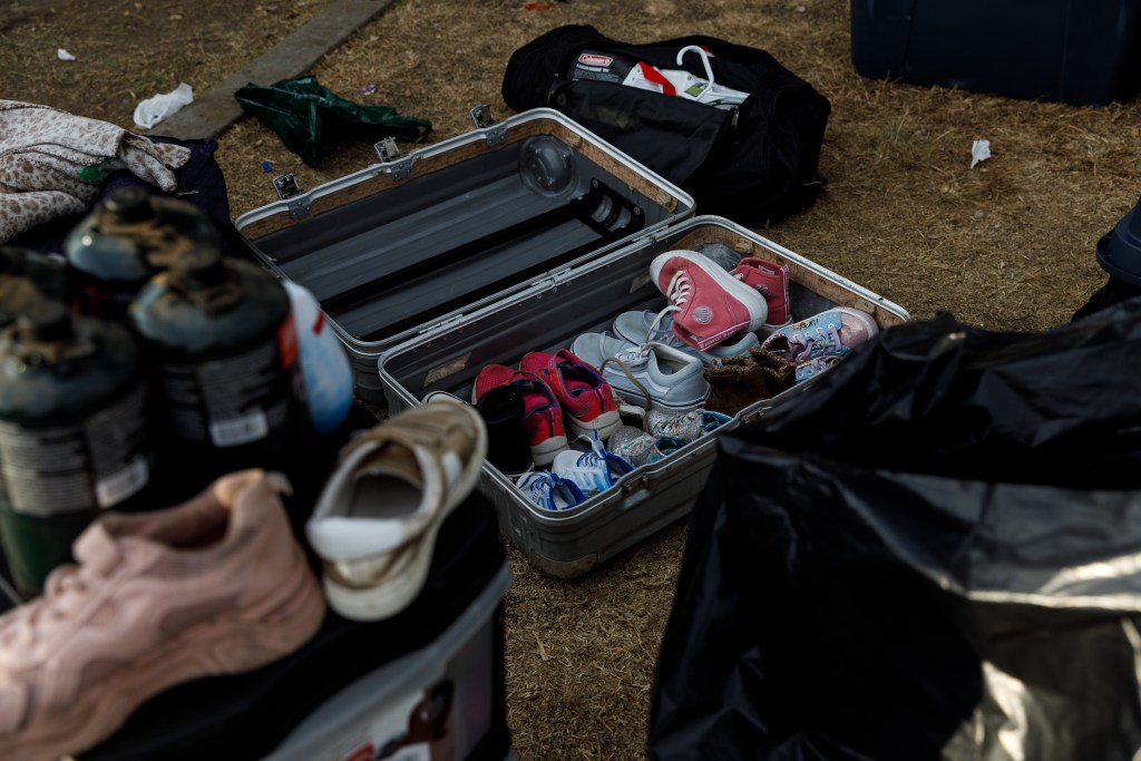 Shoes inside a suitcase at a park where asylum-seeking families have been living in tents in San Diego on Aug. 7, 2024./ Photo by Kristian Carreon for Voice of San Diego
