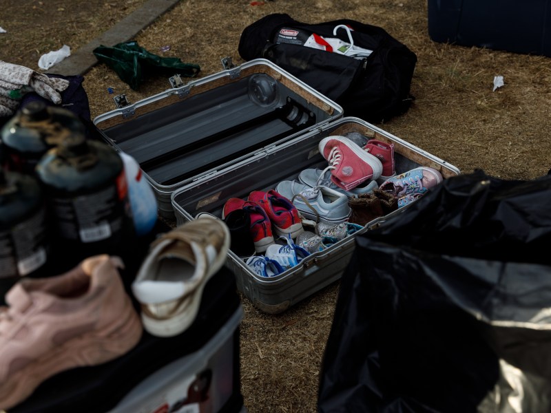 Shoes inside a suitcase at a park where asylum-seeking families have been living in tents in San Diego on Aug. 7, 2024./ Photo by Kristian Carreon for Voice of San Diego